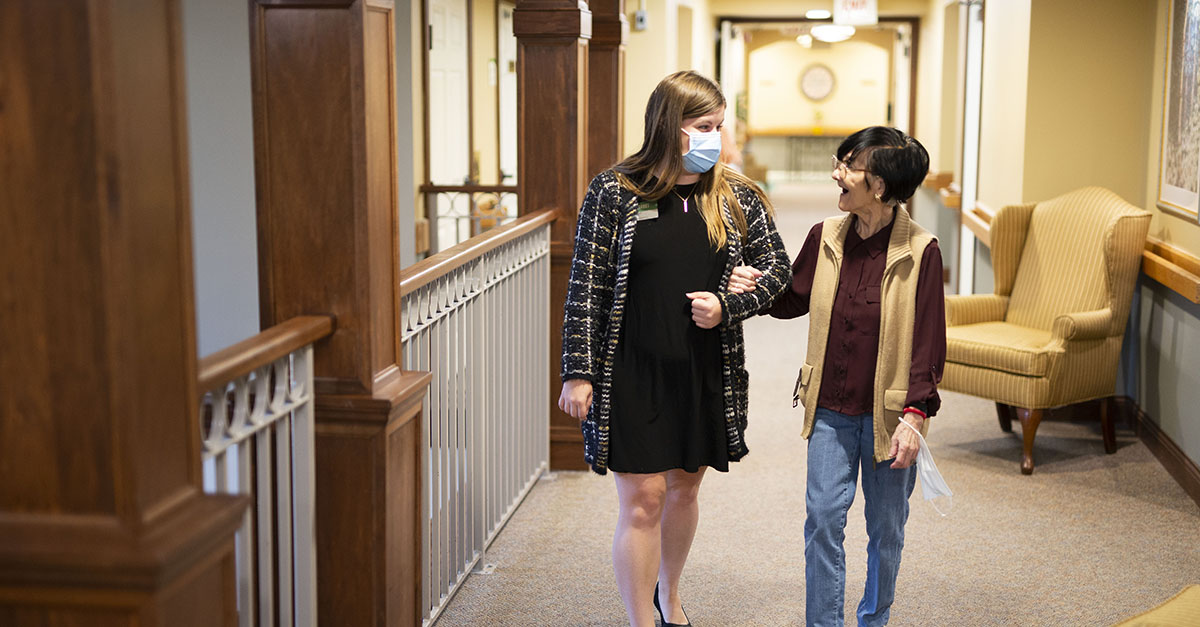 An Atria Senior Living resident and employee enjoying a walk around the community.